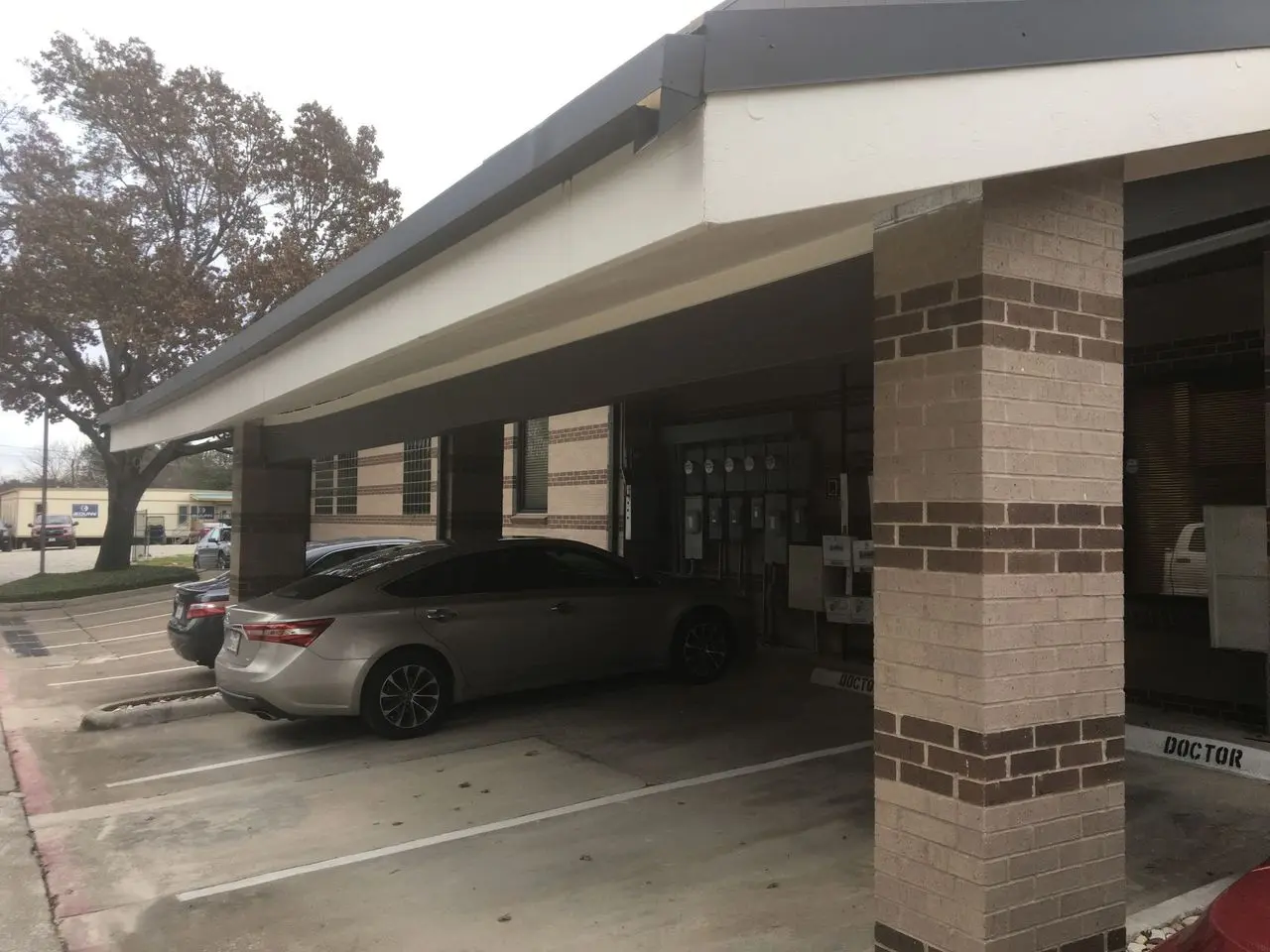 Steel carport with brick columns shading parked cars