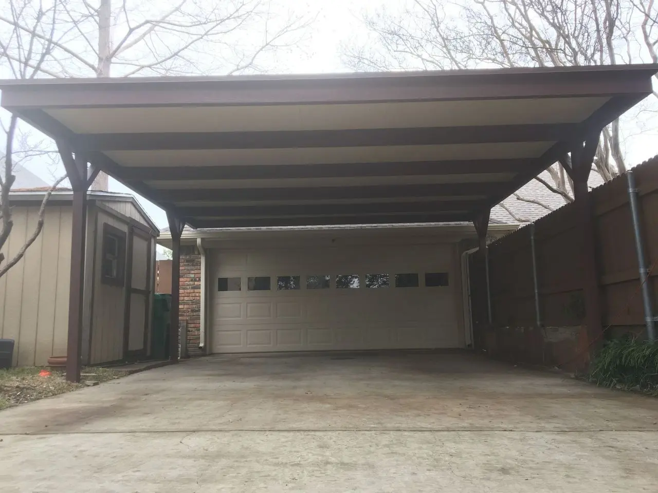 Dark steel carport covering the driveway in front of a two-car garage