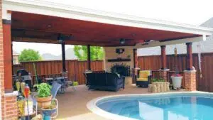 Covered poolside patio with red-stained posts and outdoor furniture