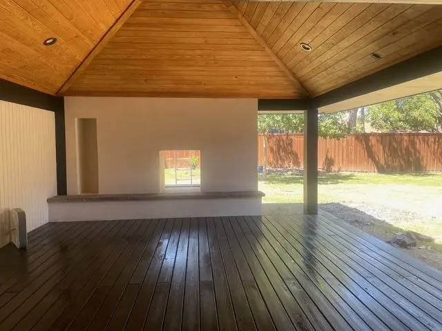 Hip-roof deck cover with a wood ceiling over a dark-stained deck floor