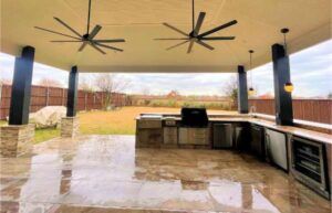 Covered outdoor kitchen with ceiling fans and stone counters