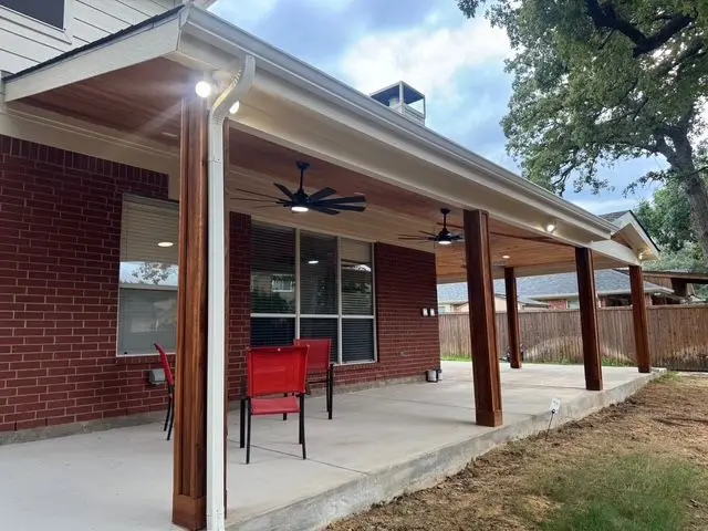 Long attached patio cover on cedar posts with ceiling fans and red patio chairs
