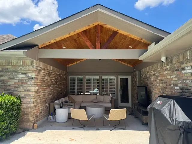 Front view of a cedar gable patio cover with lounge chairs and a grill