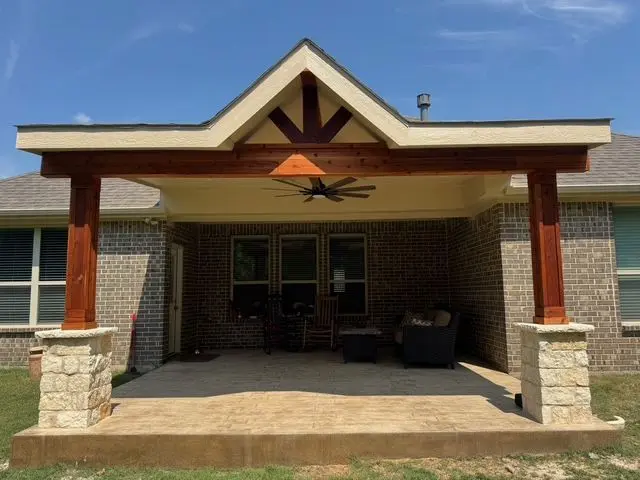Gable patio cover with cedar posts on stone bases and a stained ceiling