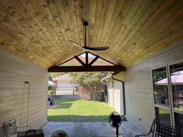 Underside of a gable patio cover with a tongue-and-groove ceiling and ceiling fan