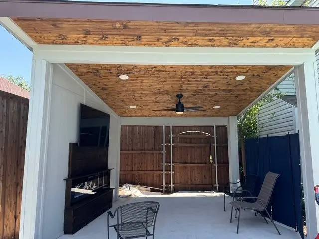 White patio cover frame with a cedar ceiling, recessed lights, and outdoor TV