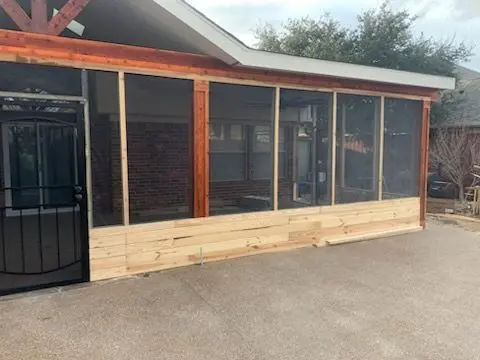Screen room with cedar trim and a black security door on a brick home
