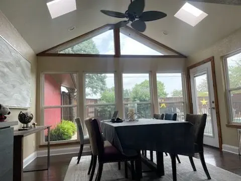 Sunroom dining area with skylights, a vaulted ceiling, and gable windows