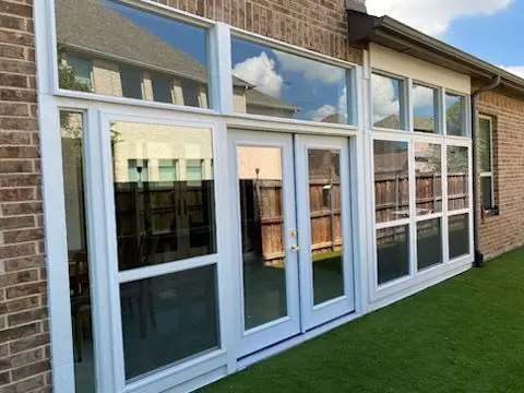 Sunroom with French doors and white-framed windows on a brick home