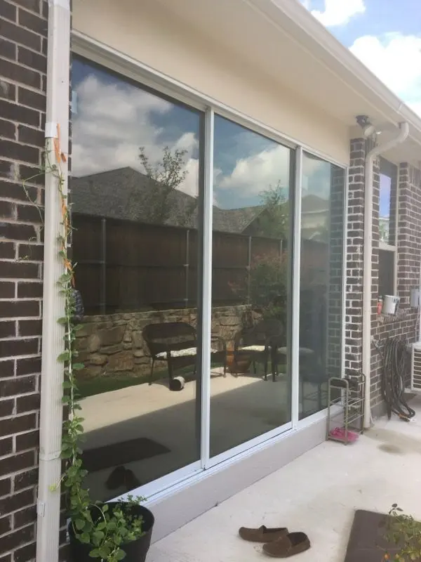 Floor-to-ceiling glass sunroom panels along a brick exterior wall