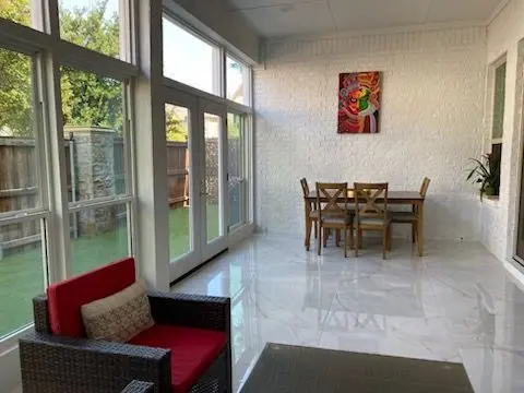 Bright sunroom with tile floors, a white brick wall, and a dining table