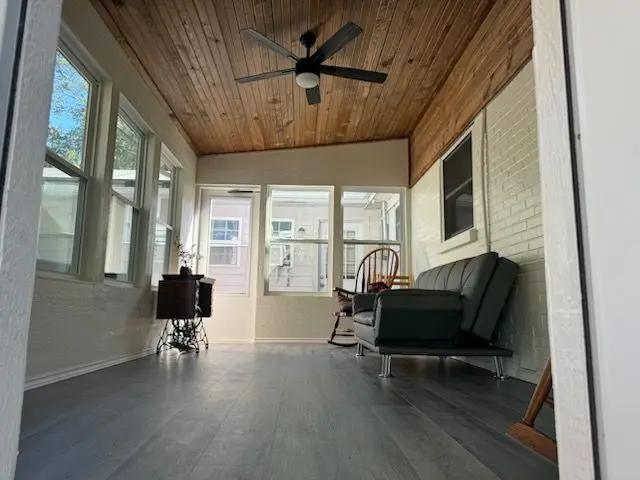 Sunroom with a wood ceiling, ceiling fan, gray floors, and a futon