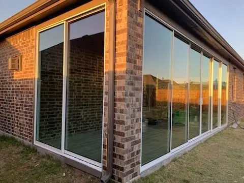 Sliding glass walls on a brick sunroom reflecting the sunset