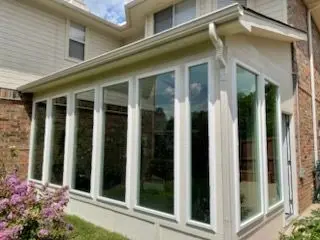 Sunroom exterior with tall white-framed windows and landscaping